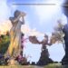 Picture of the outside of the Daggerfall Estate in ESO. There is a giant statue of Dibella with her base covered in beautiful flowers. In the background a statue of a dragon is breathing out orange fire.